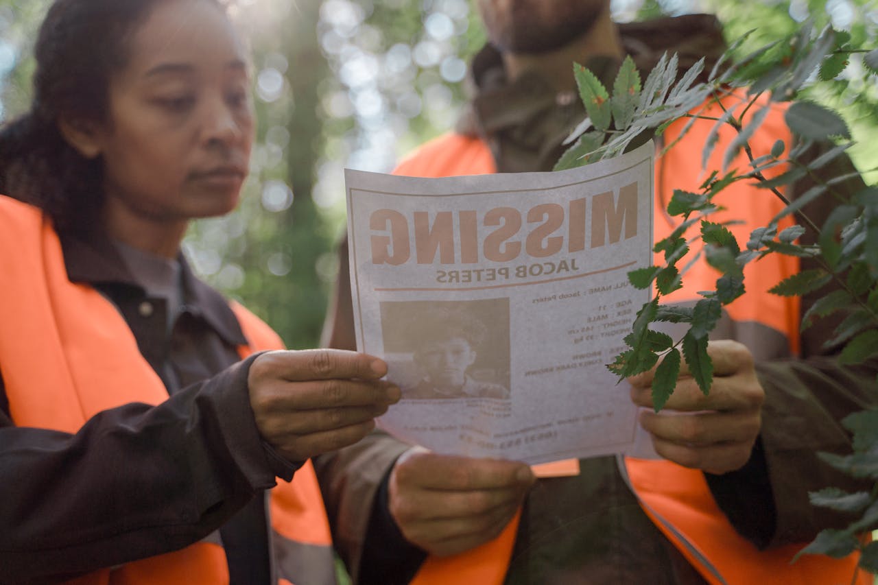 Volunteers in forest holding a missing person poster during search operation.